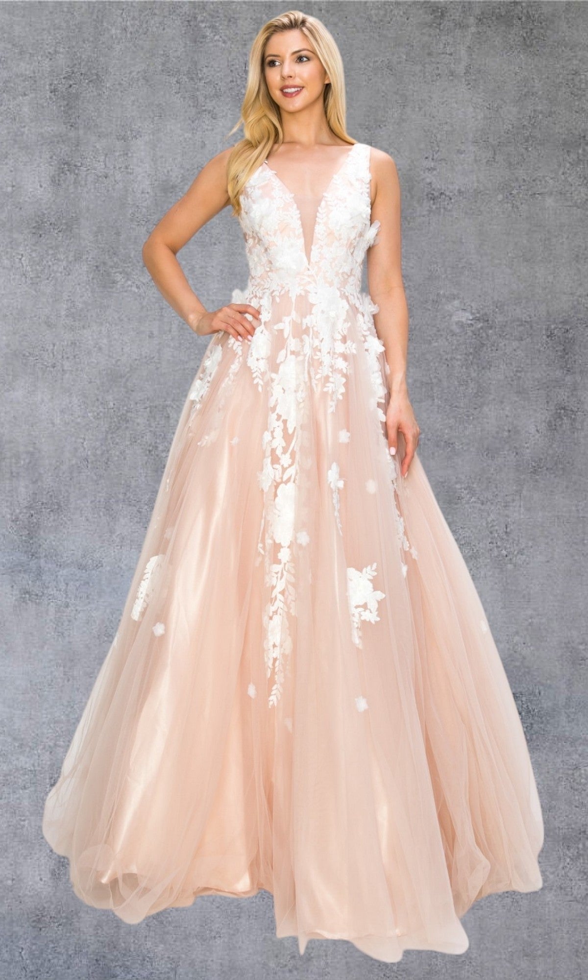 A woman is wearing the Long Formal Dress: Cinderella Couture 8040J, a sleeveless, floor-length blush pink ball gown embellished with stunning 3D floral lace appliques, as she stands against a gray textured background.